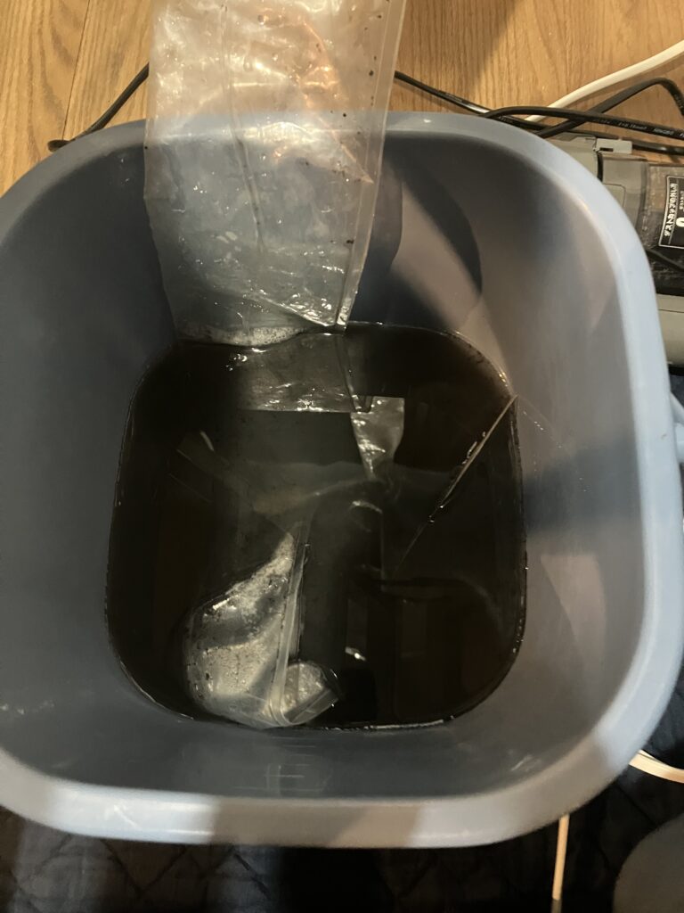 エアコンクリーニングで発生した汚水。カビ汚れがひどく真っ黒。