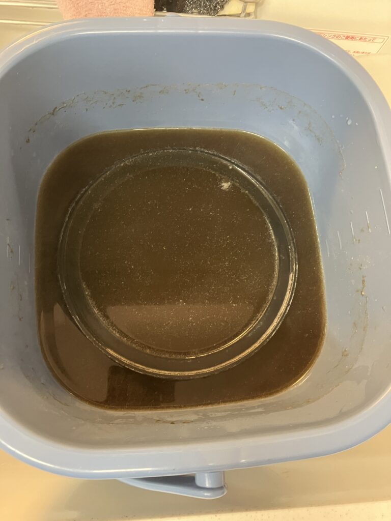 換気扇シロッコファンの漬け込み開始時の写真。お湯が真っ黒になりました。